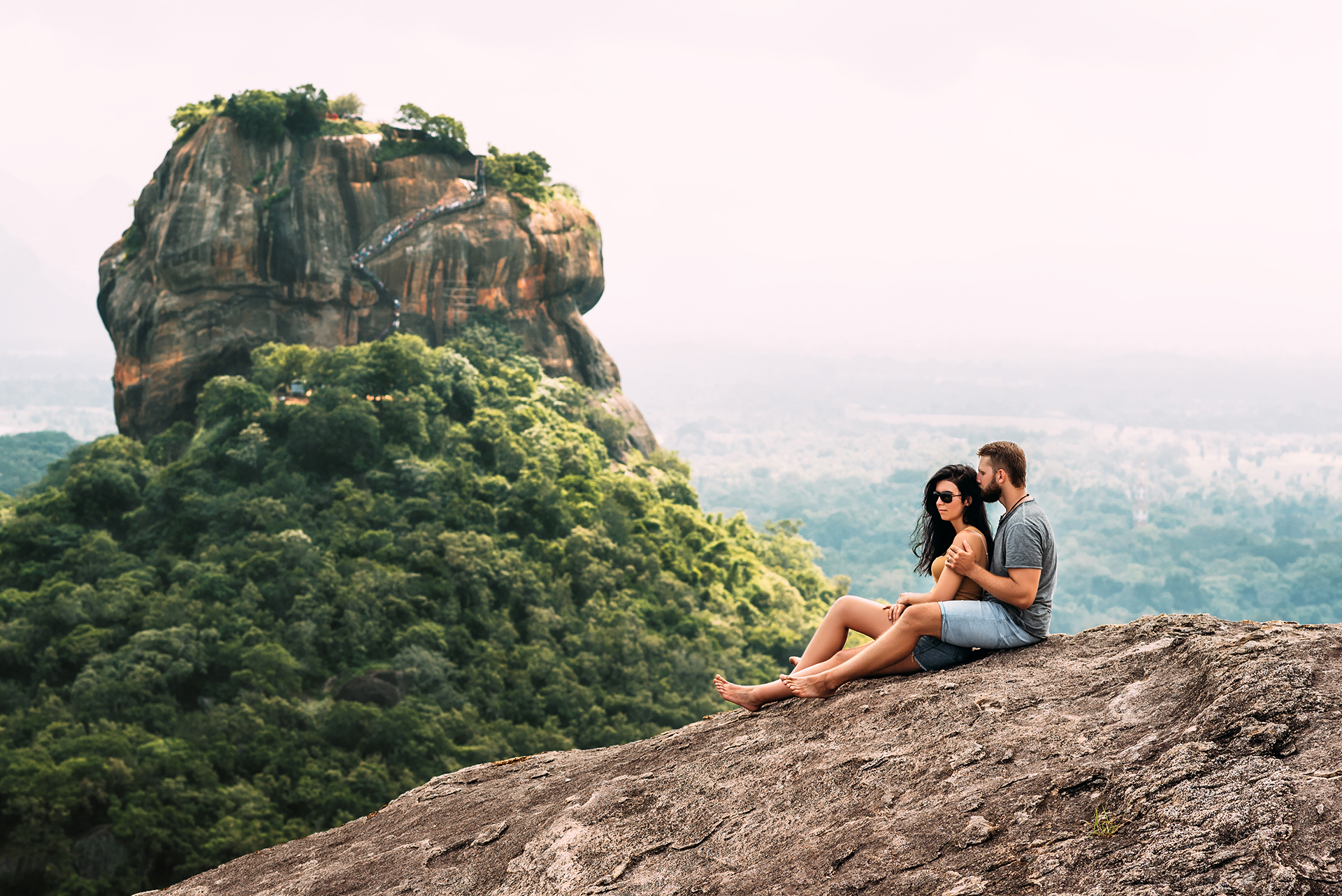 A couple in love on a rock admires the beautiful views. Boy and girl on the rock. A couple in love travels. Couple in Sri Lanka. Honeymoon in Asia. Man and woman in Sigiriya. Couple in the mountains